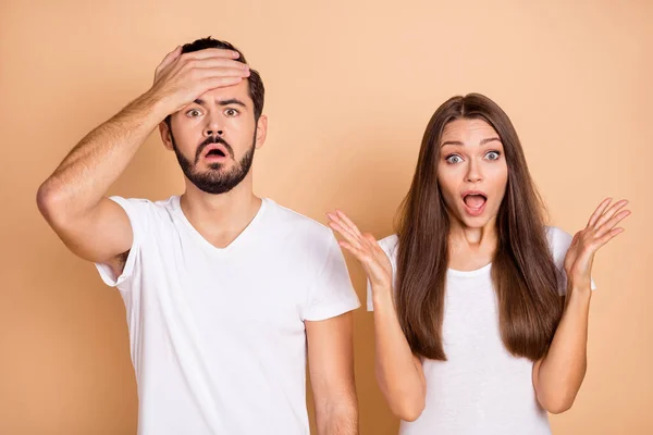 Foto de marido impresionado molesto esposa usar camisetas blancas levantamiento brazos cabeza aislado color beige fondo — Foto de Stock