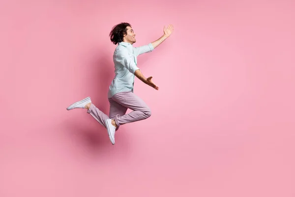 Perfil de cuerpo completo lado de la foto de hombre alegre joven loco divertido salto mirada espacio vacío usar pantalones aislados sobre fondo de color rosa —  Fotos de Stock