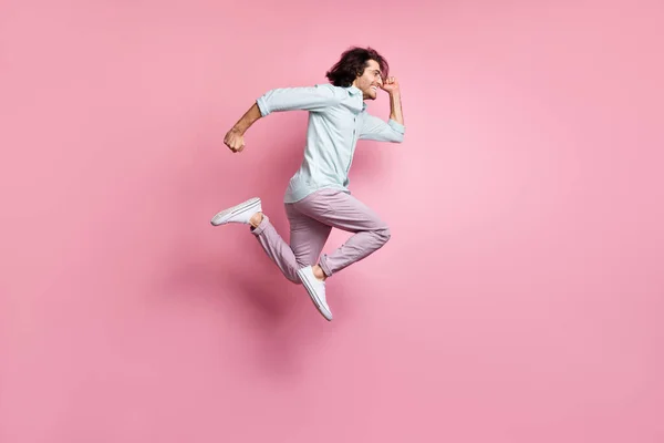 Full size profil boční fotografie mladého vzrušeného muže skok nosit fialové kalhoty bílé boty vypadají copyspace izolované na růžové barevné pozadí — Stock fotografie
