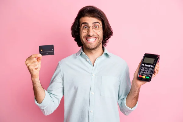 Portret van jonge knappe opgewonden dolblij man man man houden credit card terminal slijtage bril geïsoleerd op roze kleur achtergrond — Stockfoto