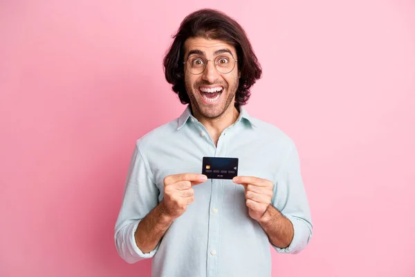 Portret van jonge knappe opgewonden glimlachen gek man man man houden credit card slijtage bril geïsoleerd op roze kleur achtergrond — Stockfoto