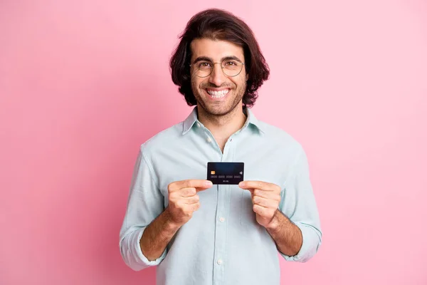 Portret van jonge knappe vrolijke glimlachende man man man houden credit card dragen bril kijken camera geïsoleerd op roze kleur achtergrond — Stockfoto