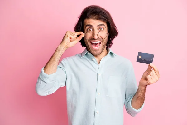 Portret van jonge knappe opgewonden gelukkig man man man houden credit card slijtage bril geïsoleerd op roze kleur achtergrond — Stockfoto