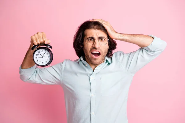 Fotografie stresu legrační chlap držet hodiny zaspání nosit brýle modrá košile izolované na růžové barvy pozadí — Stock fotografie
