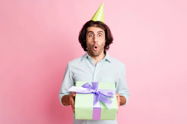 Foto de alegre chico de pelo castaño fresco celebrar dando regalo gafas de desgaste gorra camisa aislada sobre fondo de color rosa pastel — Foto de Stock