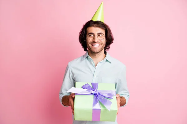 Φωτογραφία του χαρούμενου funky καφέ μαλλιά τύπος δίνοντας δώρο φορούν γυαλιά πουκάμισο καπέλο απομονώνονται σε παστέλ ροζ χρώμα φόντο — Φωτογραφία Αρχείου