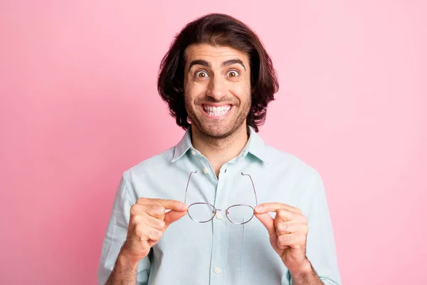 Photo de belles mains de personne tiennent des lunettes toothy sourire amélioration de la vue isolé sur fond de couleur rose — Photo