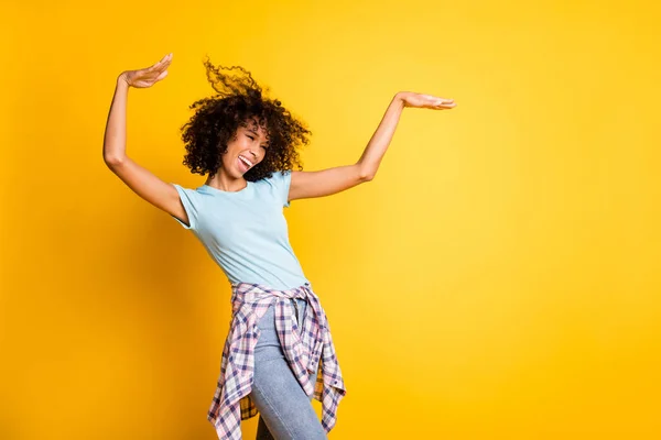 Foto de despreocupado encantador pele escura encaracolado menina vestida azul t-shirt dançando espaço vazio isolado cor amarela fundo — Fotografia de Stock