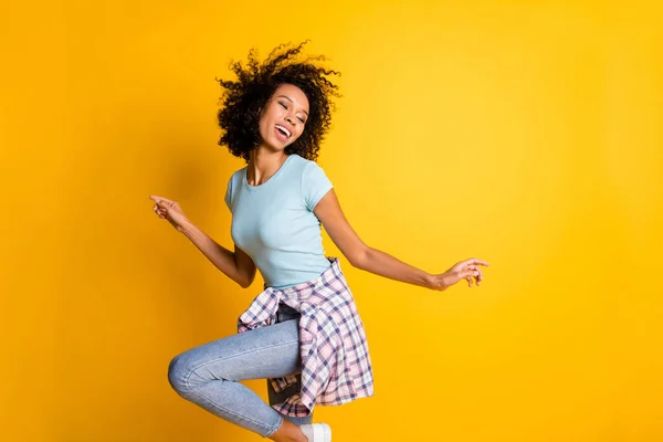 Photo of charming adorable dark skin wavy lady wear blue t-shirt dancing isolated yellow color background — Stock Photo, Image
