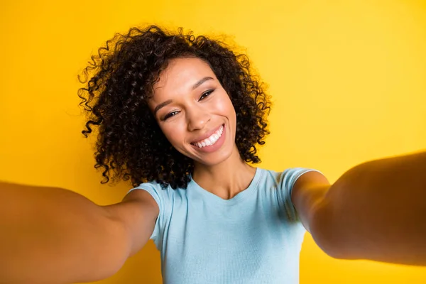 Kuva kiiltävä makea tumma iho aaltoileva nainen käyttää sininen t-paita ottaen selfie kamera eristetty keltainen väri tausta — kuvapankkivalokuva