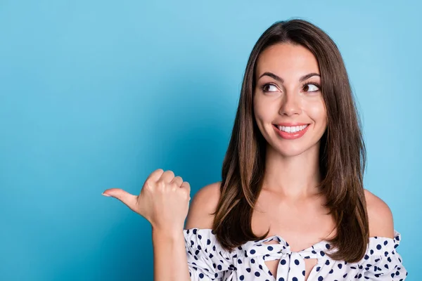 Foto de engraçado jovem senhora indicar polegar olhar vazio espaço brilhante sorriso desgaste pontilhado blusa isolado azul cor de fundo — Fotografia de Stock