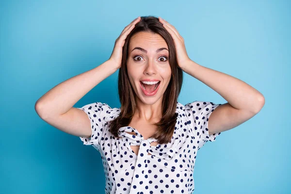 Foto von erstaunt jungen Mädchen offenen Mund Handflächen Kopf Blick Kamera tragen gepunktete Bluse isoliert blaue Farbe Hintergrund — Stockfoto