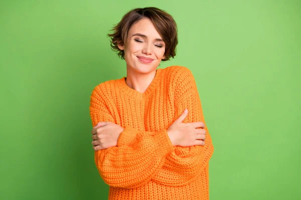 Portret optymistycznej brunetki przytulić się nosić pomarańczowy sweter odizolowany na pastelowym tle zielony kolor — Zdjęcie stockowe