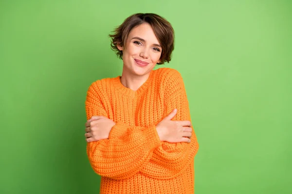 Foto de jovem feliz positivo muito encantadora menina encantadora em suéter laranja abraço abraçar-se isolado no fundo de cor verde — Fotografia de Stock