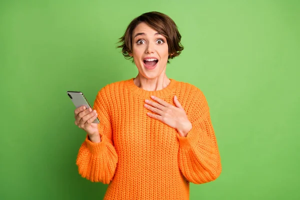 Фото здивованої шокованої молодої жінки тримає телефонну реакцію, як сповіщення ізольовано на фоні зеленого кольору — стокове фото