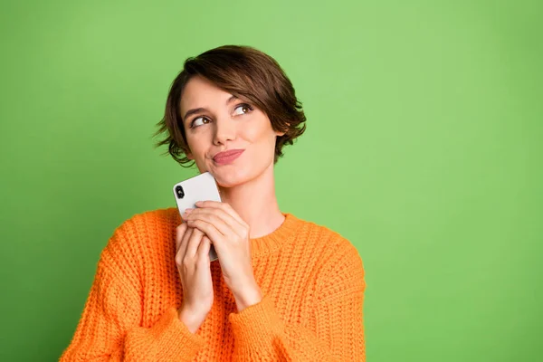 Foto di sognante creativo giovane signora sguardo spazio vuoto tenere il telefono immaginare post isolato su sfondo di colore verde — Foto Stock