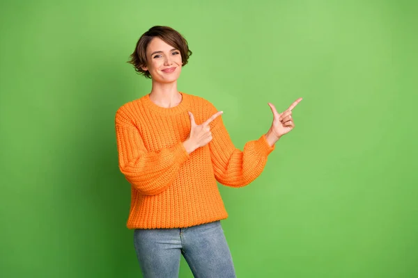 Foto de mujer joven promotora atractiva feliz apuntar los dedos espacio vacío aislado sobre fondo de color verde —  Fotos de Stock