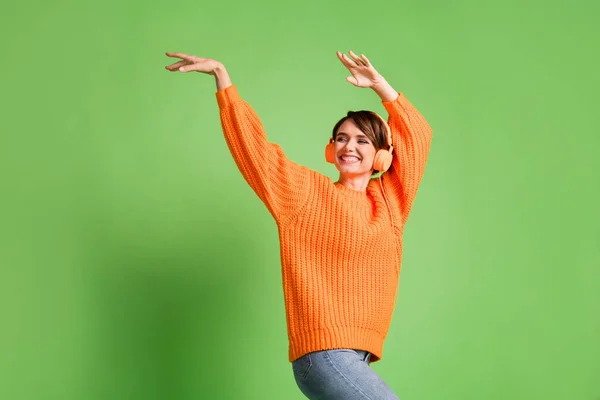 Foto de funky feliz dama encantadora mirada espacio vacío levantar manos danza escuchar música aislada sobre fondo de color verde — Foto de Stock