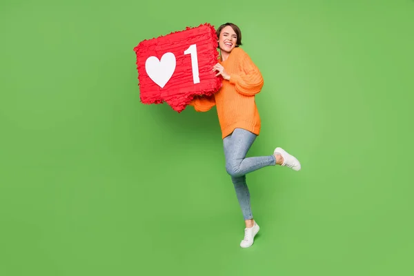 Foto em tamanho completo de jovem atraente sorridente menina alegre segurar enorme como ícone pinata isolado no fundo de cor verde — Fotografia de Stock