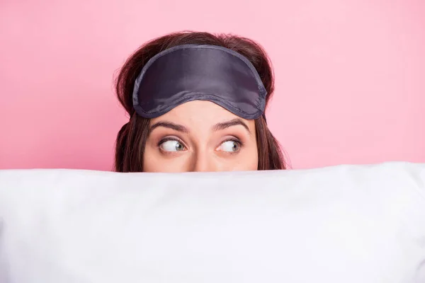 Foto retrato de la mujer escondida detrás de la almohada mirando a un lado aislado sobre fondo de color rosa pastel — Foto de Stock