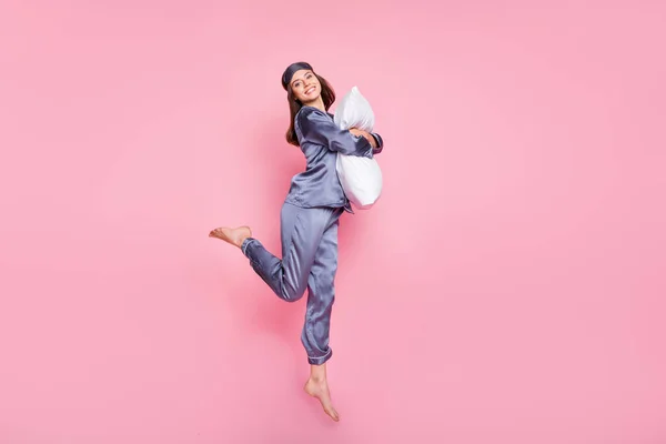 Lunghezza totale dimensioni del corpo foto di ragazza che indossa pigiama abbracciando cuscino saltando isolato su sfondo rosa pastello — Foto Stock