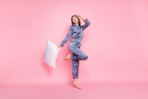 フル長さボディサイズの写真の女の子身に着けていますナイトウェアを身に着けている枕ジャンプ見て空白のスペース孤立したパステルピンク色の背景 — ストック写真
