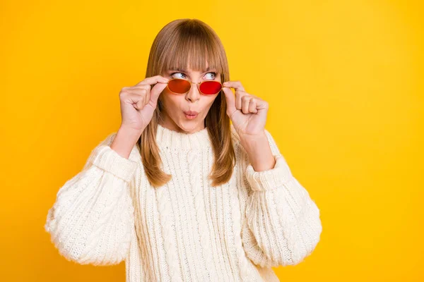 Ritratto di stupefatto signora braccia toccare occhiali da sole sguardo vuoto spazio usura pullover isolato su sfondo di colore giallo — Foto Stock