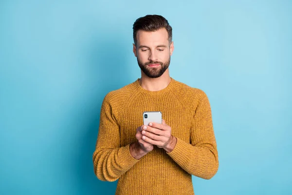 Retrato de cara focado atraente vestindo camisola de malha casual usando dispositivo navegar na web isolado sobre fundo de cor azul brilhante — Fotografia de Stock