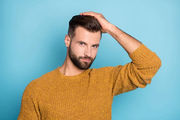 Фото молодого харизматичного привлекательного привлекательного мужчину, который фиксирует прическу трикотажным свитером на голубом фоне — стоковое фото