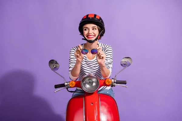 Portretowe zdjęcie ciekawej szczęśliwej dziewczyny w kasku na motocyklu uśmiechniętej patrząc na pustą przestrzeń odizolowaną na żywym fioletowym tle — Zdjęcie stockowe