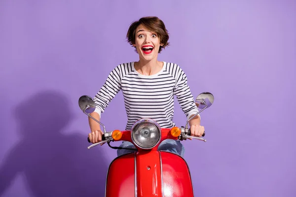 Foto van opgewonden grappig meisje rijden motor open mond slijtage gestreept shirt geïsoleerde paarse kleur achtergrond — Stockfoto
