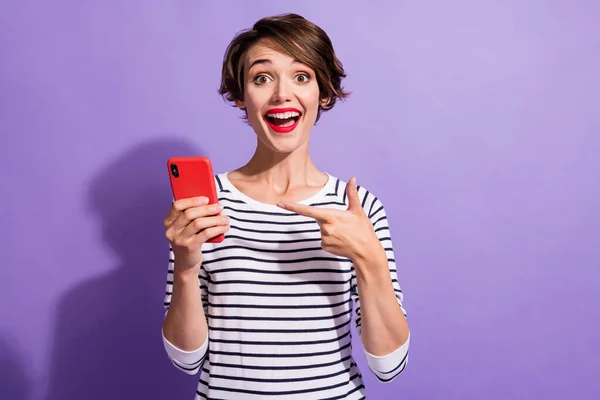 Фото веселої молодої леді тримає телефон прямого пальця в смугастій сорочці ізольований фіолетовий кольоровий фон — стокове фото