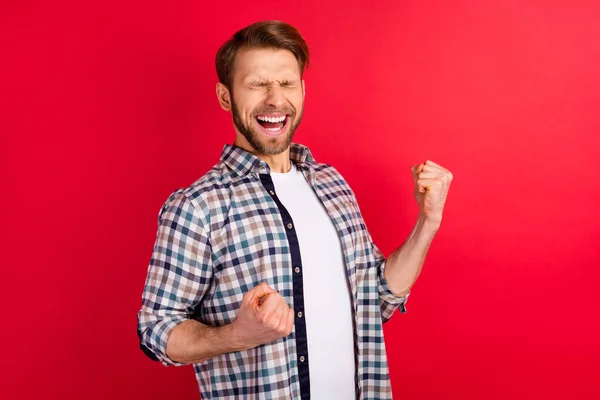 Fénykép a fiatal jóképű férfi izgatott őrült boldog pozitív mosoly Örülj győzelem ököllel kéz elszigetelt piros szín háttér — Stock Fotó