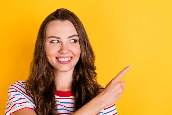 Foto van glanzende schattige jonge vrouw dragen gestreepte outfit wijzend op zoek lege ruimte geïsoleerde gele kleur achtergrond — Stockfoto