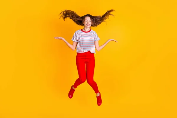 Foto de senhora alegre salto jogar cabelo desgaste listrado camisa calças vermelhas sapatos isolados cor amarela fundo — Fotografia de Stock