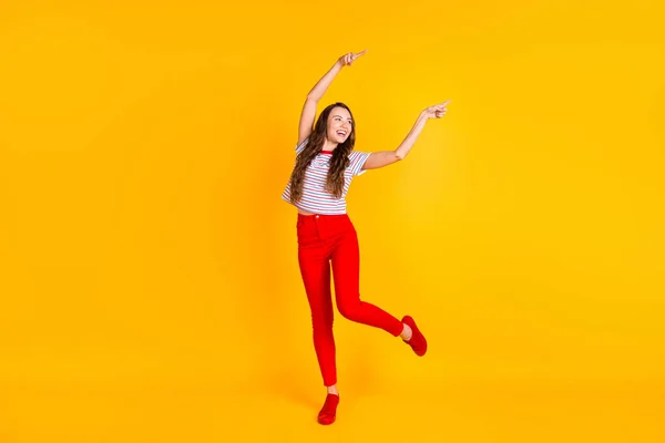 Foto de cuerpo completo de la joven alegre sonrisa alegre mirada positiva indican los dedos espacio vacío aislado sobre fondo de color amarillo —  Fotos de Stock