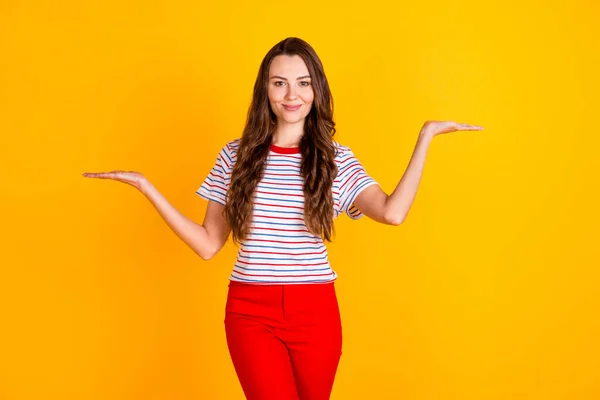 Portret van aantrekkelijke zelfverzekerde vrolijke meisje houden op twee palmen kopiëren lege ruimte advertentie bieden geïsoleerd over levendige gele kleur achtergrond — Stockfoto