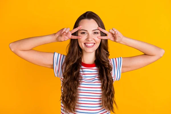 Portret van aantrekkelijke vrolijke blij meisje tonen dubbele v-teken in de buurt van oog goed humeur hebben plezier geïsoleerd over helder gele kleur achtergrond — Stockfoto