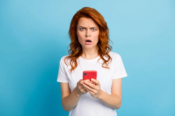 Foto portret van ongelukkige meisje met telefoon in twee handen geïsoleerd op pastel blauw gekleurde achtergrond — Stockfoto