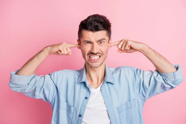 Foto de chico enojado irritado infeliz cerca de los dedos oídos ruido fuerte aislado en el fondo de color rosa — Foto de Stock