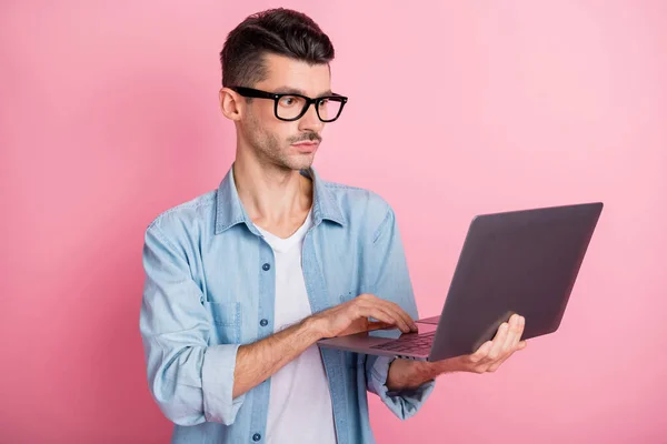 专心致志的英俊商人拿着笔记本电脑，在粉红的背景上孤零零地写着 — 图库照片
