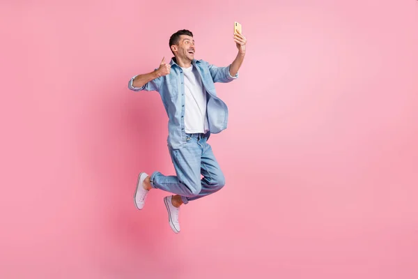 Lunghezza completa foto di marrone capelli uomo fare selfie pollice su usura blu camicia jeans salto aria isolato su sfondo di colore rosa — Foto Stock