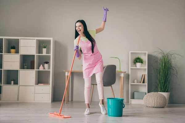 Full length body size view of pretty cheerful crazy girl maid using mop like mic singing song hit having fun at light interior room — Stock Photo, Image
