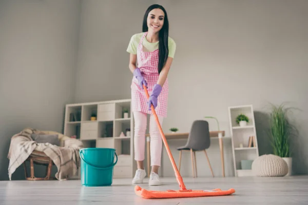 Longitud completa vista del tamaño del cuerpo de bastante alegre chica de pelo largo criada disfrutando de limpieza ordenada piso en la habitación interior de luz — Foto de Stock