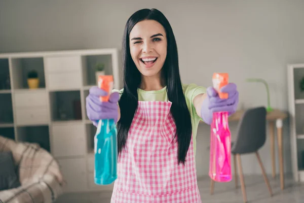 Portrait of charming cheerful long-haired maid holding in hands using pulverizers inking having fun at light interior living-room — Stock Photo, Image