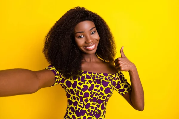 Auto-retrato de atraente alegre menina de cabelos ondulados na moda mostrando anúncio de polegar isolado sobre vibrante fundo de cor amarela — Fotografia de Stock