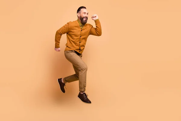 Foto de perfil em tamanho completo de homem cabelo marrom otimista salto desgaste marrom calças de camisola sapatos isolados no fundo cor bege — Fotografia de Stock