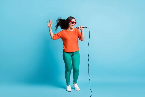 Portret van grappige aantrekkelijke dame dragen donkere bril zingen feesten genieten geïsoleerd op blauwe kleur achtergrond — Stockfoto
