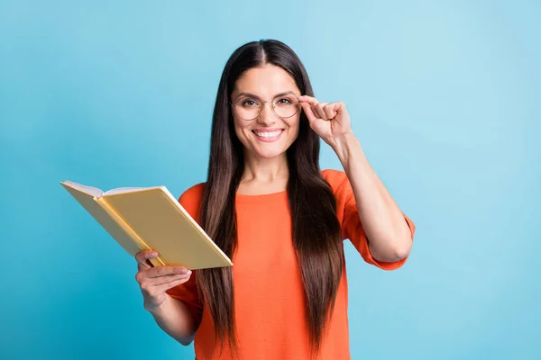 Portrét inteligentní osoby zubatý úsměv ruka dotýkající se brýle držet knihu izolované na modrém pozadí — Stock fotografie