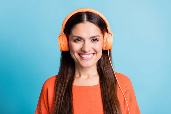 可爱的心满意足的女人的橙色耳机的照片，在蓝色背景下被隔离的微笑 — 图库照片